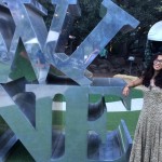 Woman posing by a statue of tilted letters